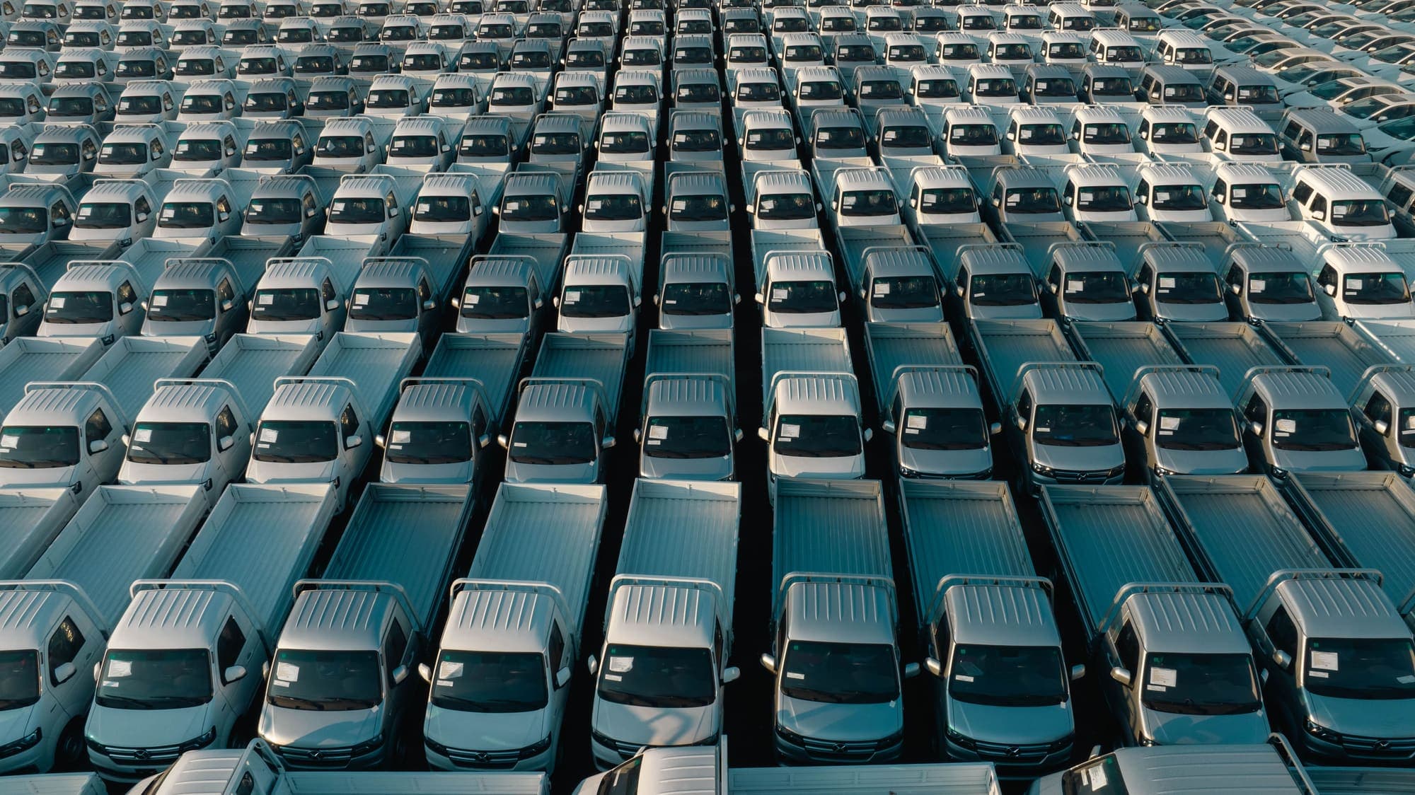 Aerial view of rows of new light commercial trucks parked in a distribution yard.